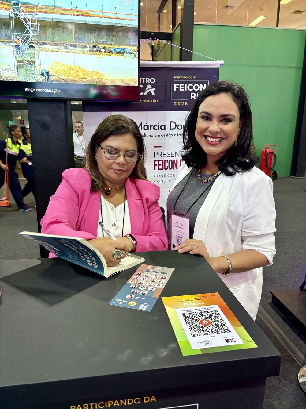Márcia Doring autografando livro, ao lado de uma profissional