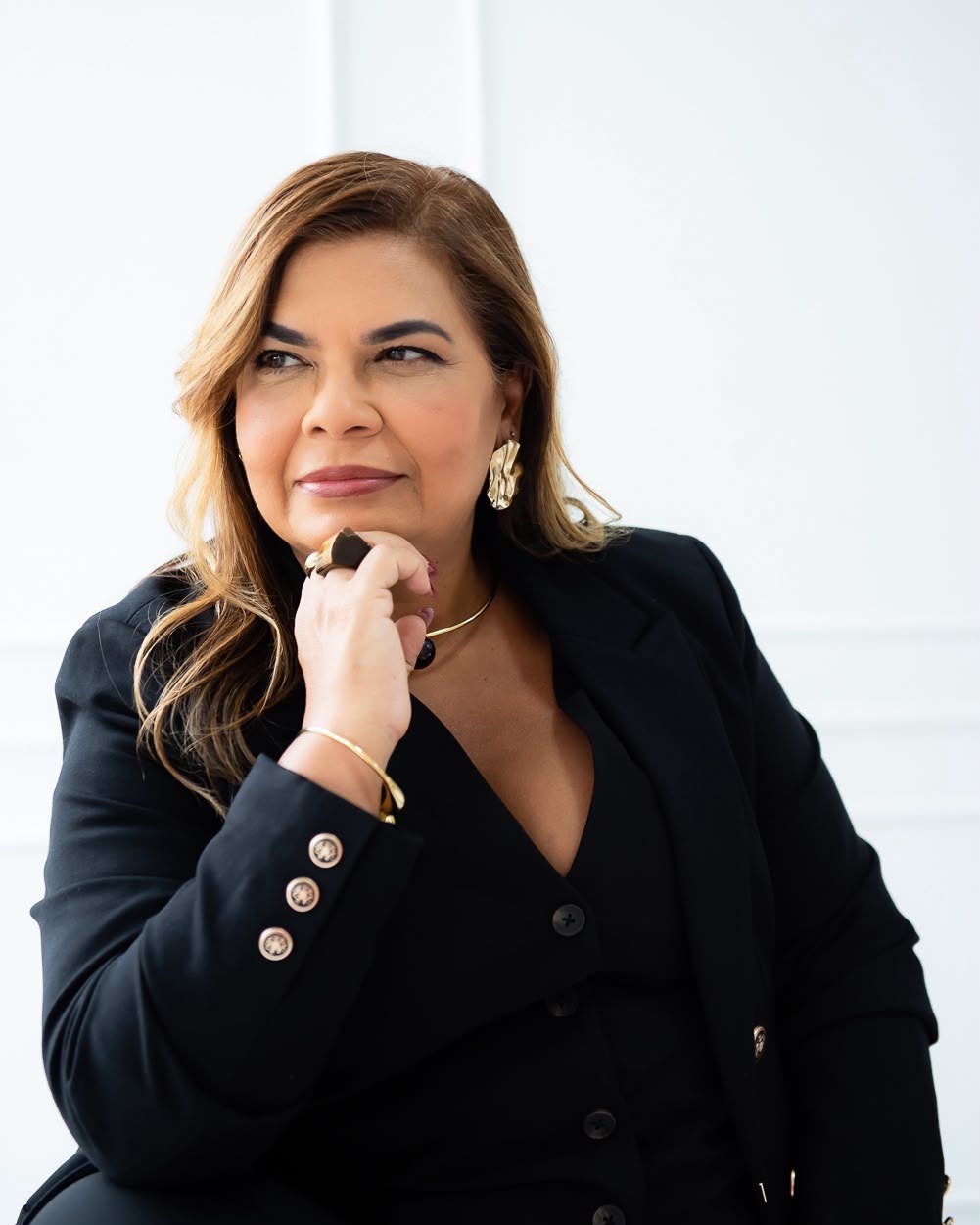 Márcia Doring de blazer preto, com a mão no queixo, olhando para o lado